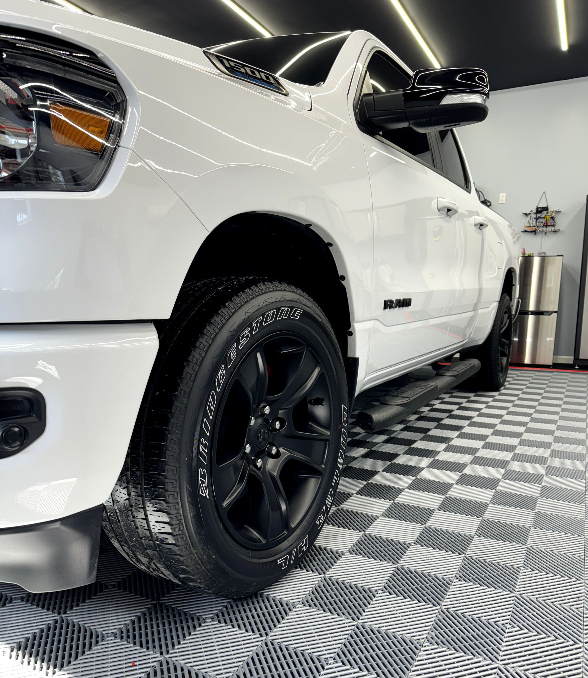 a white truck is parked on a checkered floor in a garage .
