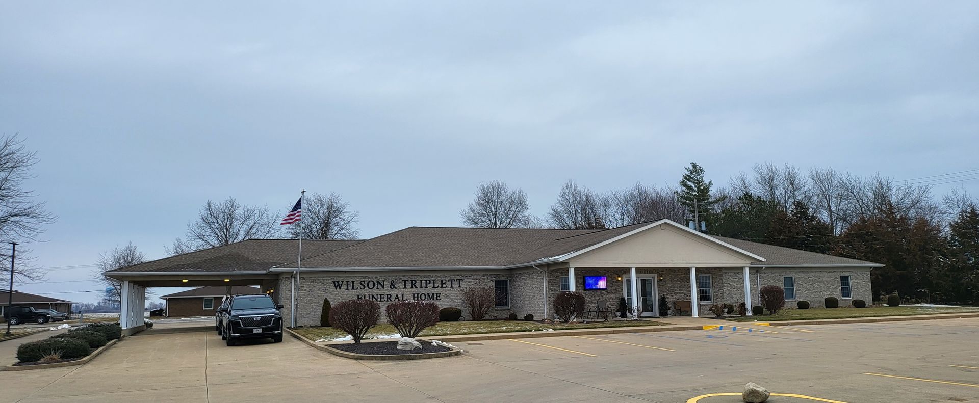 Single-story brick building with a covered entrance and parked vehicles in front