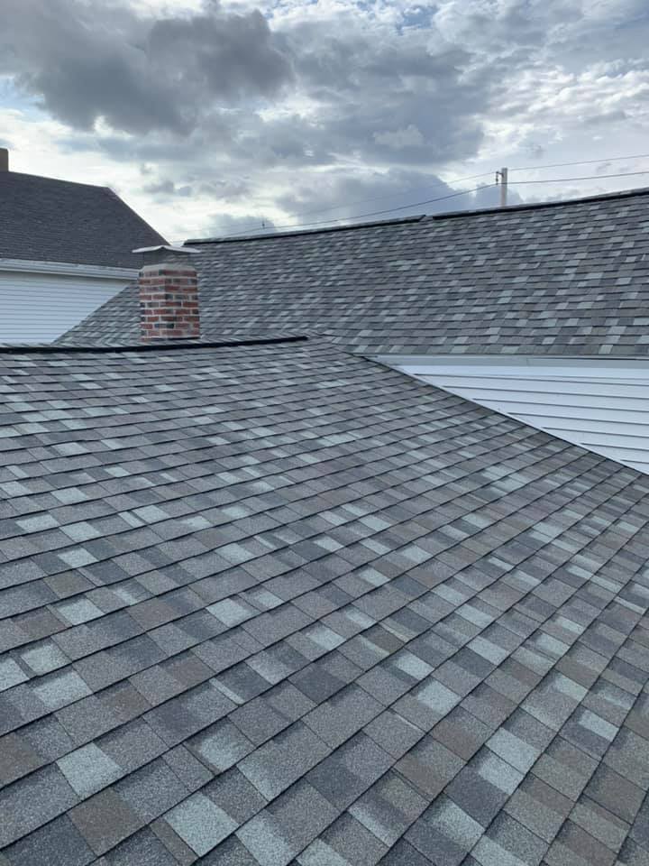 A close up of a roof with a chimney on a cloudy day.