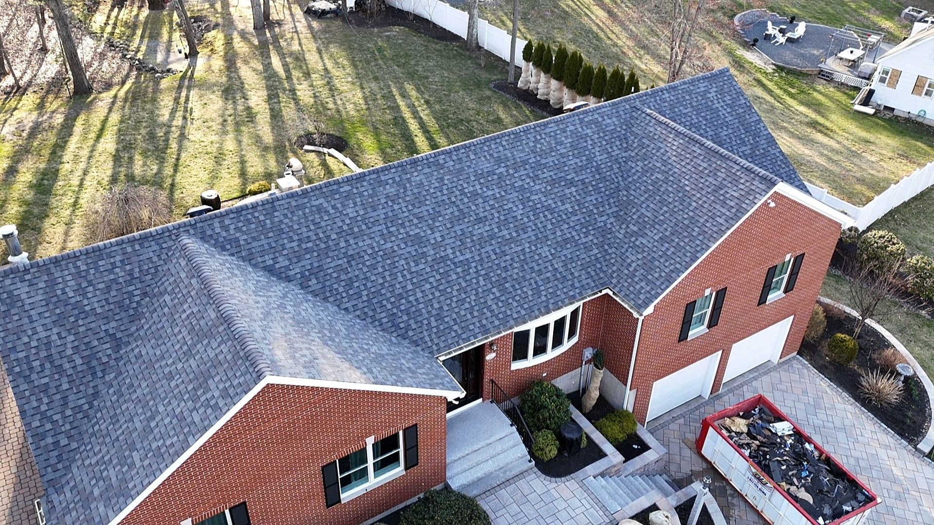 An aerial view of a brick house with a new roof.