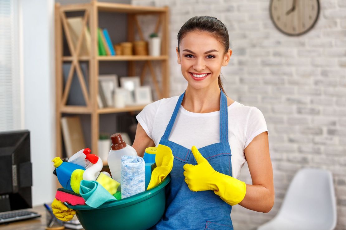 Woman in apron and gloves holding cleaning supplies, giving thumbs up. Woman in apron and gloves holding cleaning supplies, giving thumbs up.