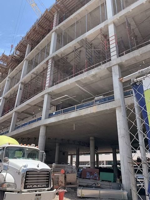 Partially built concrete parking structure with construction equipment and trucks at street level