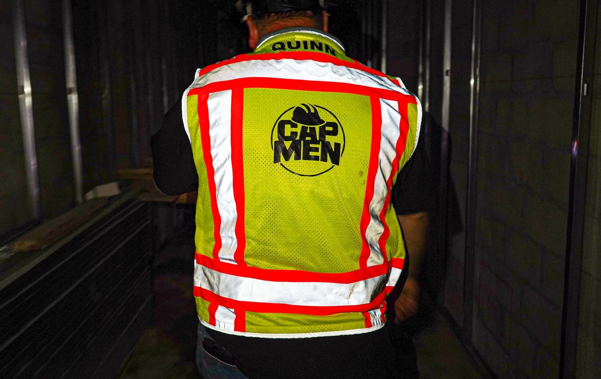 Worker in a yellow high-visibility vest walking through a dark tunnel.