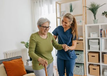 A nurse is helping an elderly woman walk with a cane. A nurse is helping an elderly woman walk with a cane.