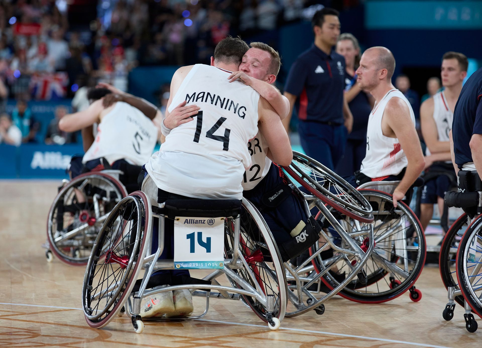 Manning with dark hair and Warburton with blondish in their wheelchairs hugging each other. Both are