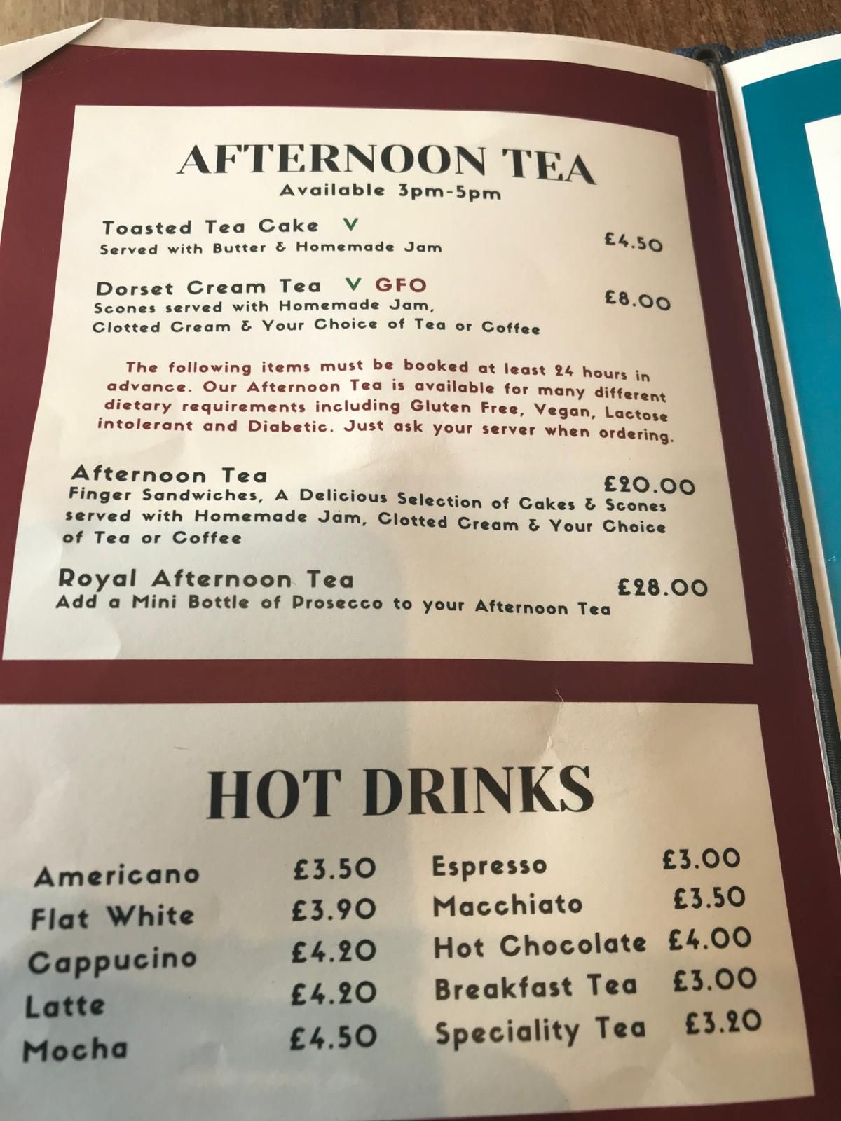 A picture of the menu stating Afternoon tea at the top and hot drinks at the bottom. The menu has a red boarded and black writing on white paper. 