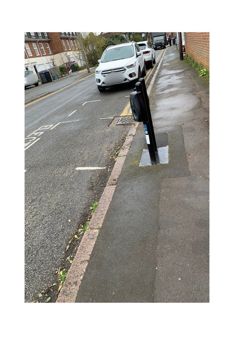 narrow street with ev chargers, parking bay with electric vehicles written on the road and cars in the back ground