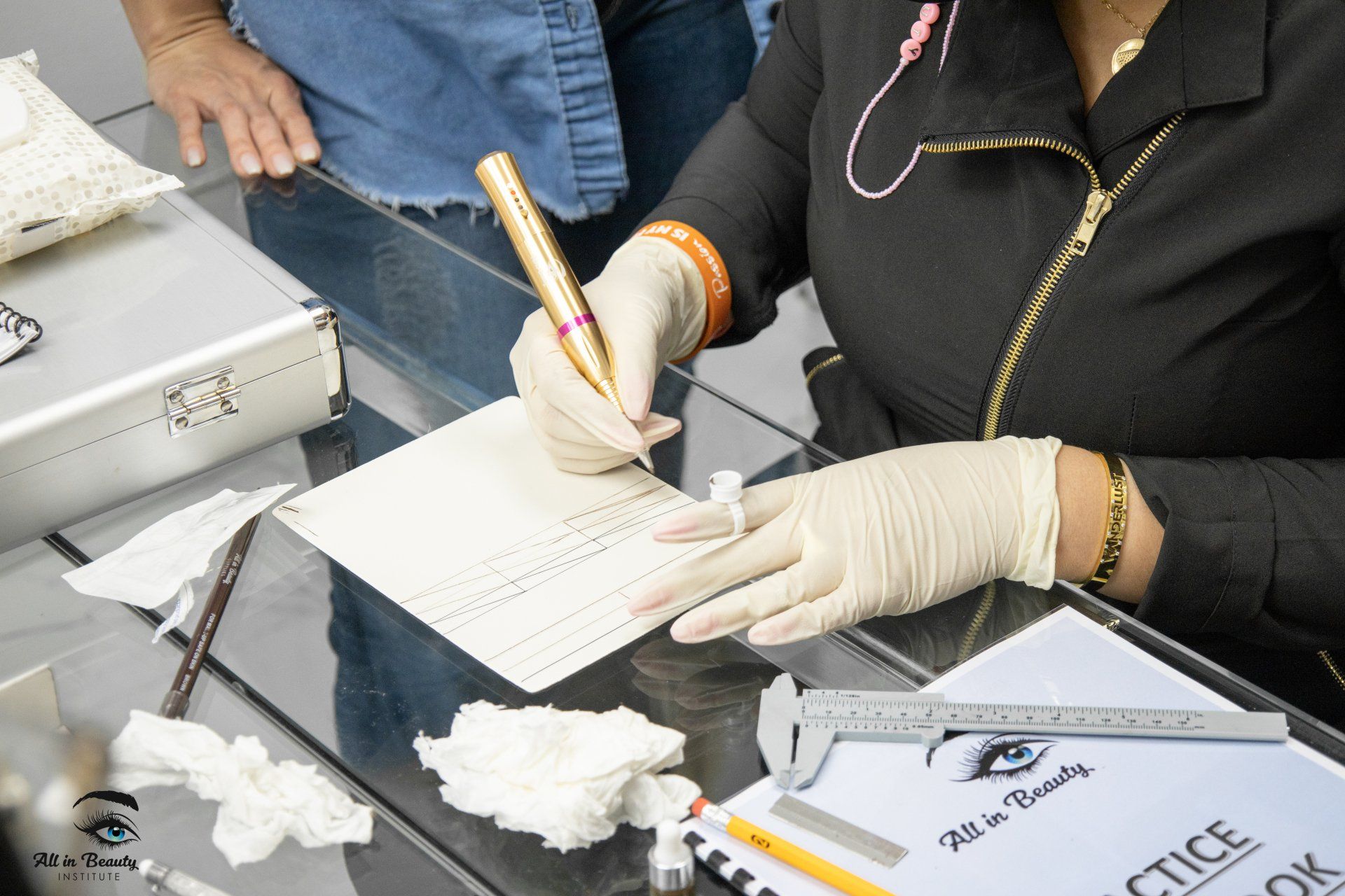 Person wearing gloves writing on paper with a pen at a beauty training class.