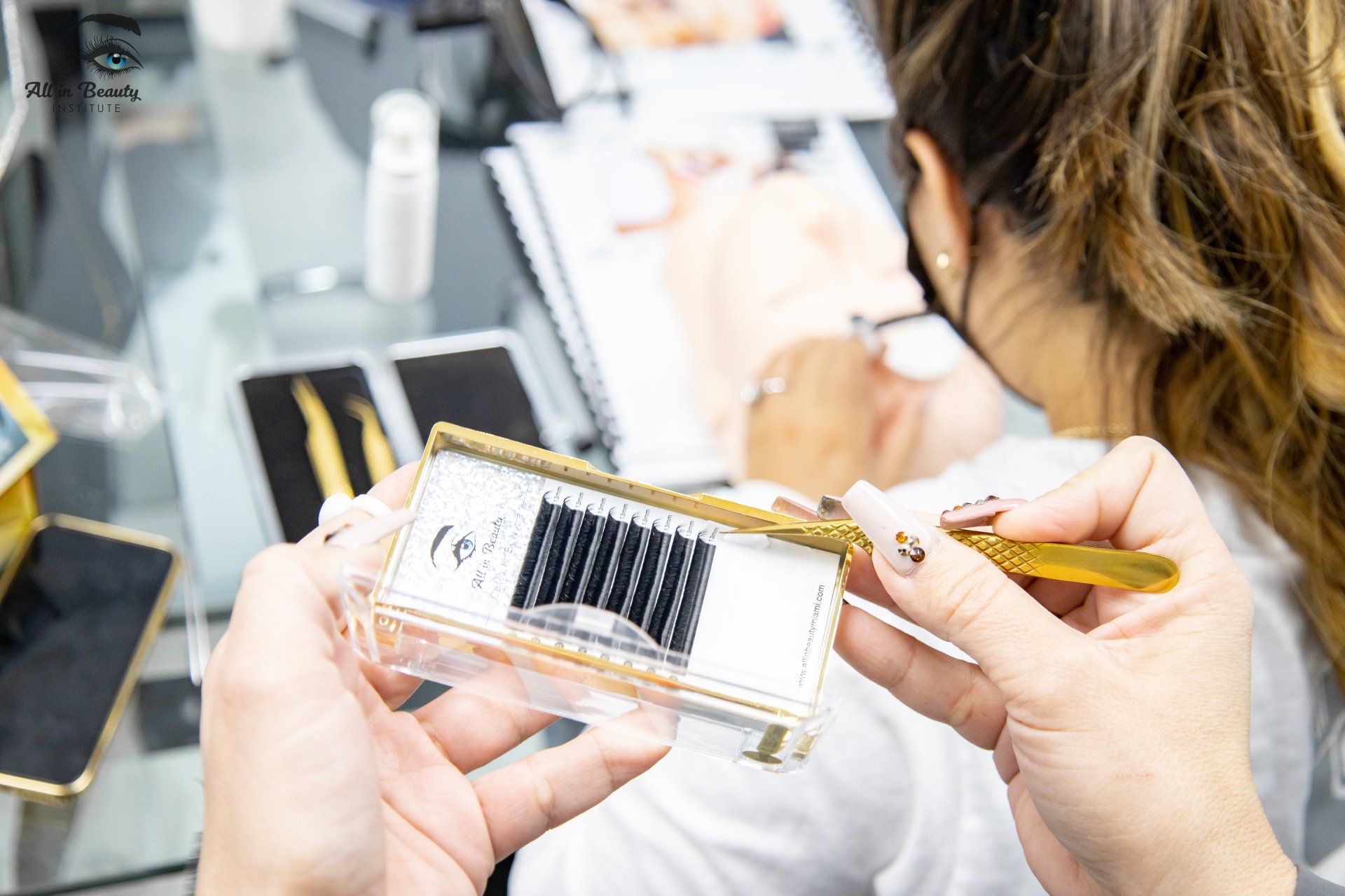 Woman holding eyelash extensions, applying them to a client with tweezers, in a beauty salon.