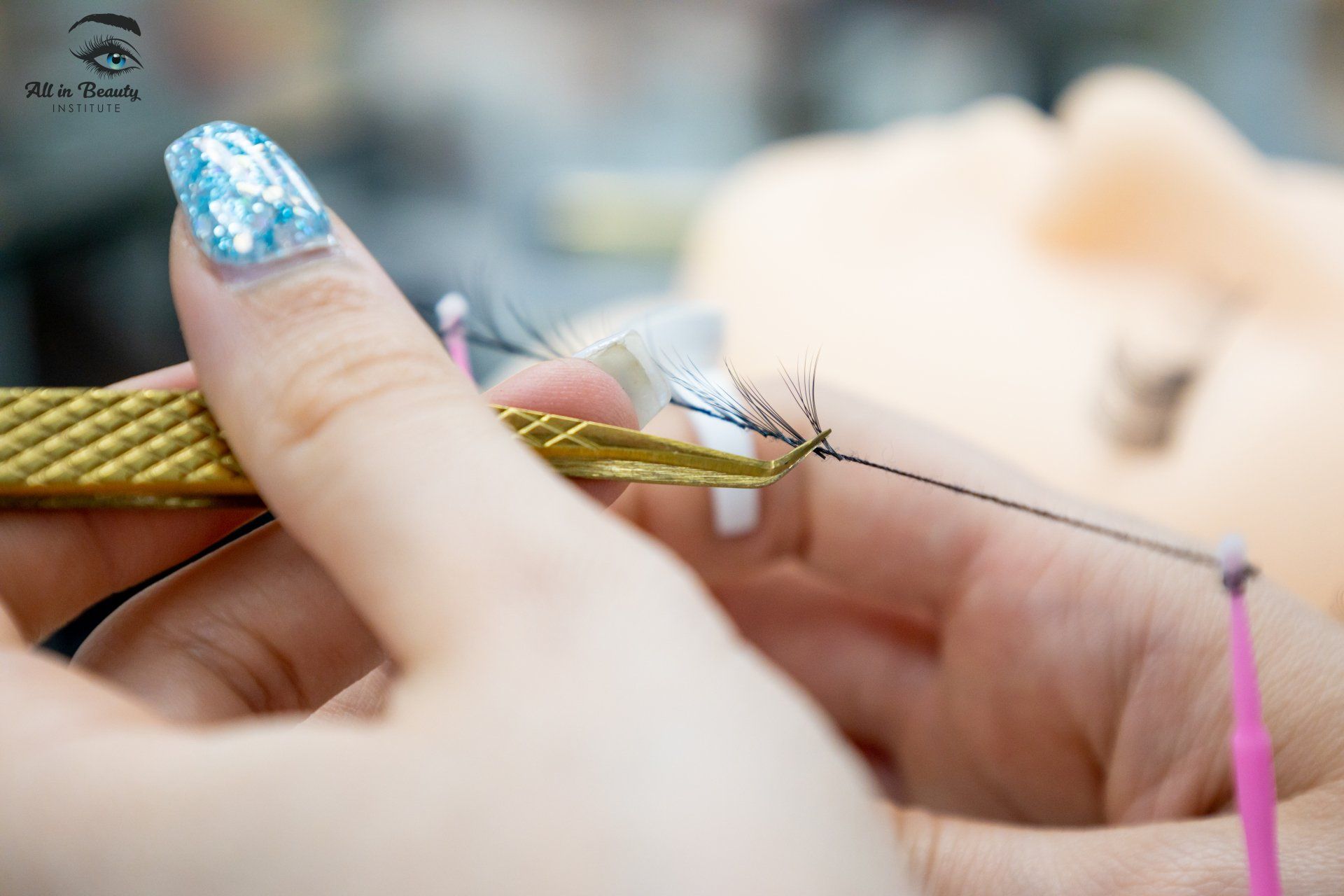 Person applying eyelash extensions with tweezers on a mannequin face.