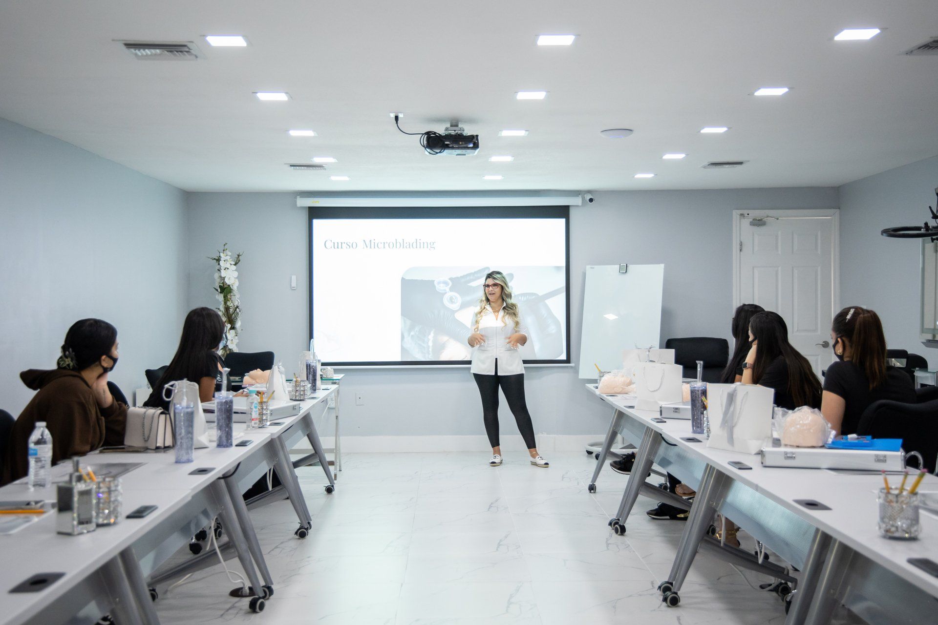 Woman giving presentation to a group in a brightly lit classroom.