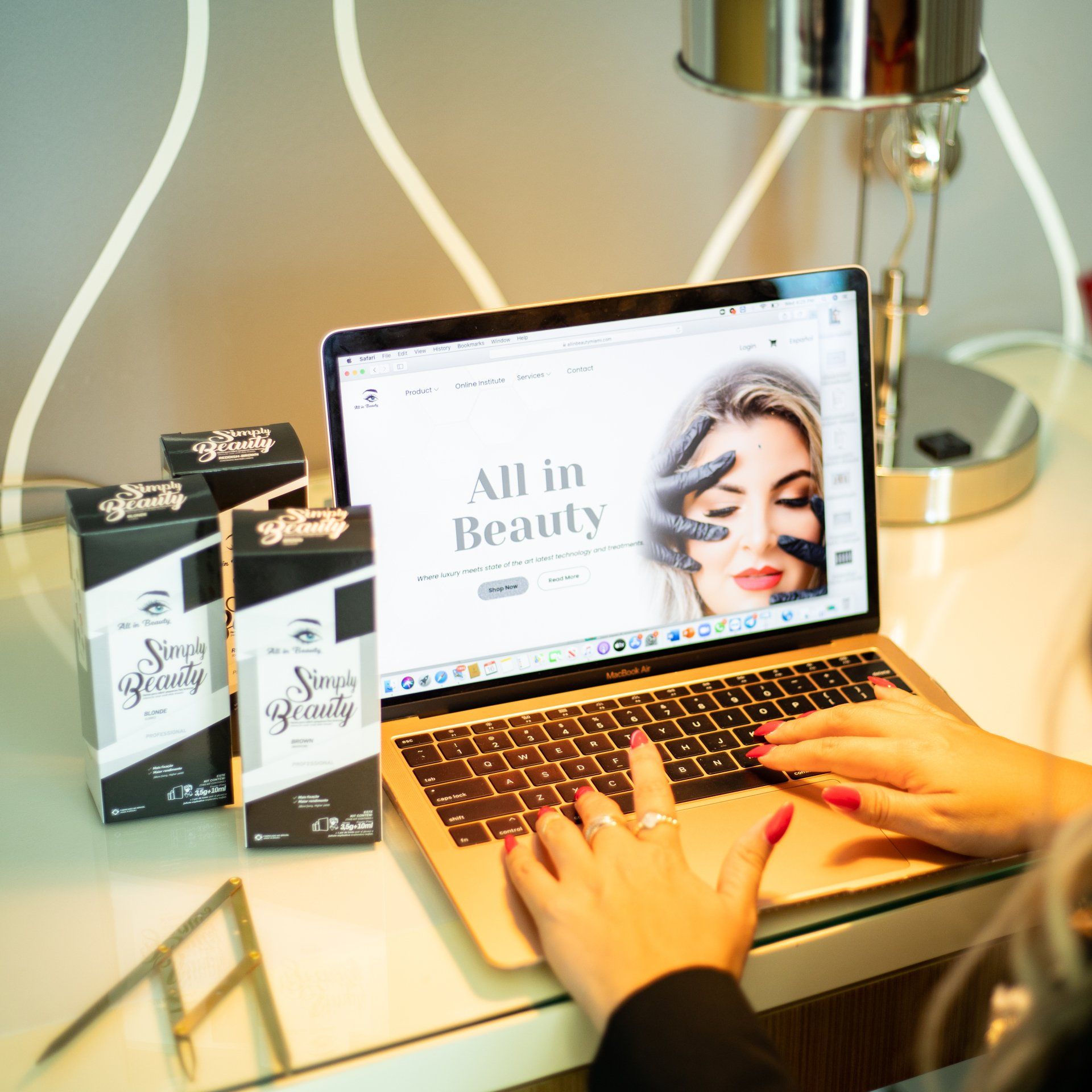 Woman using laptop, browsing beauty website, with product boxes on a desk.