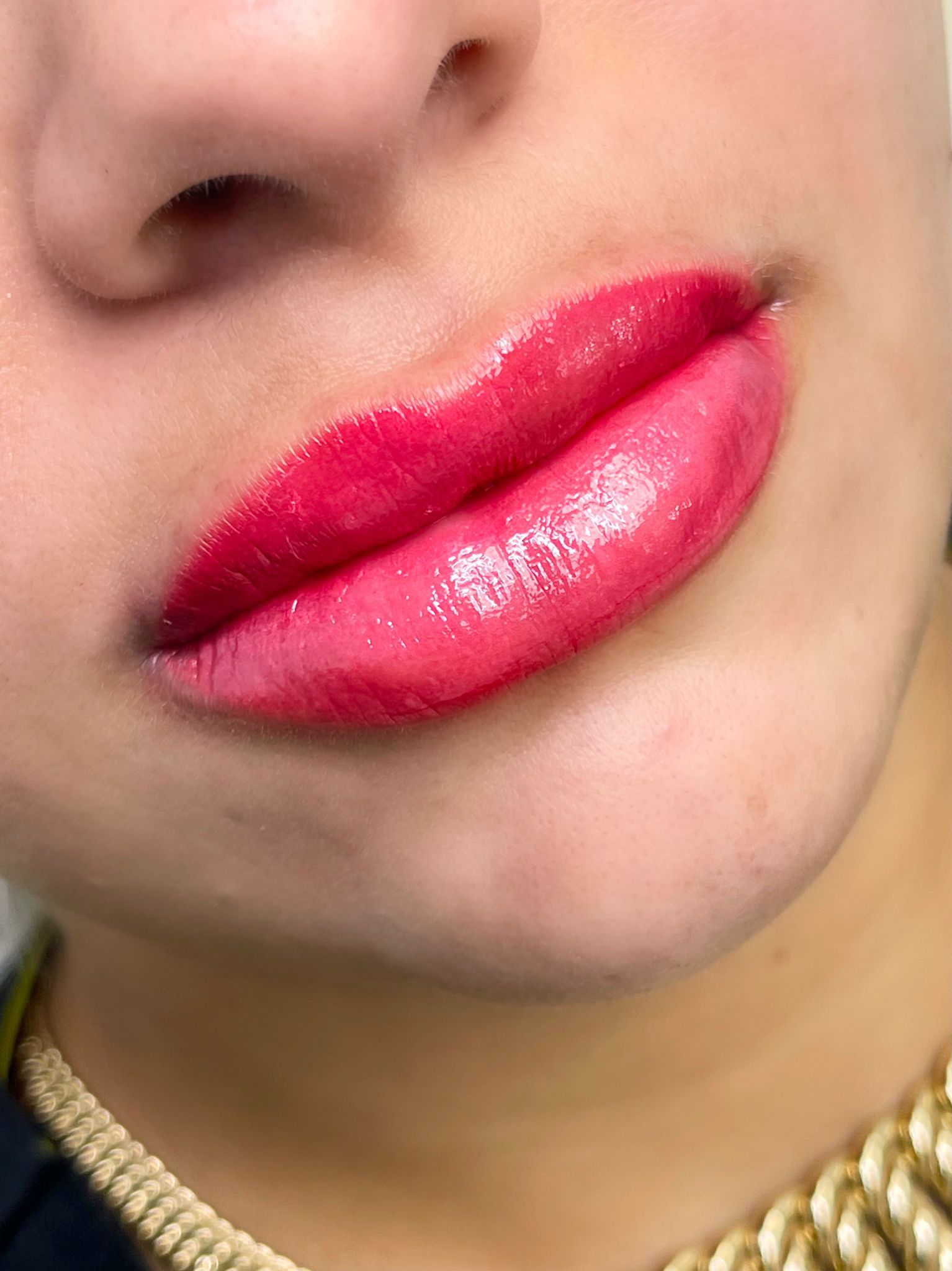 Close-up of a person's lips. They are a bright pink ombre with a glossy finish.