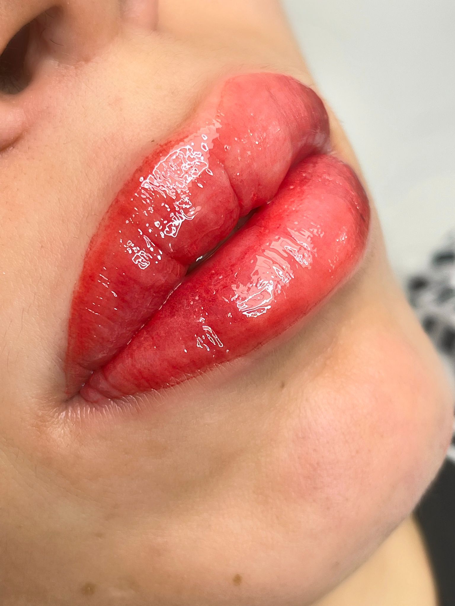 Close-up of full, glossy red lips on a person's face.