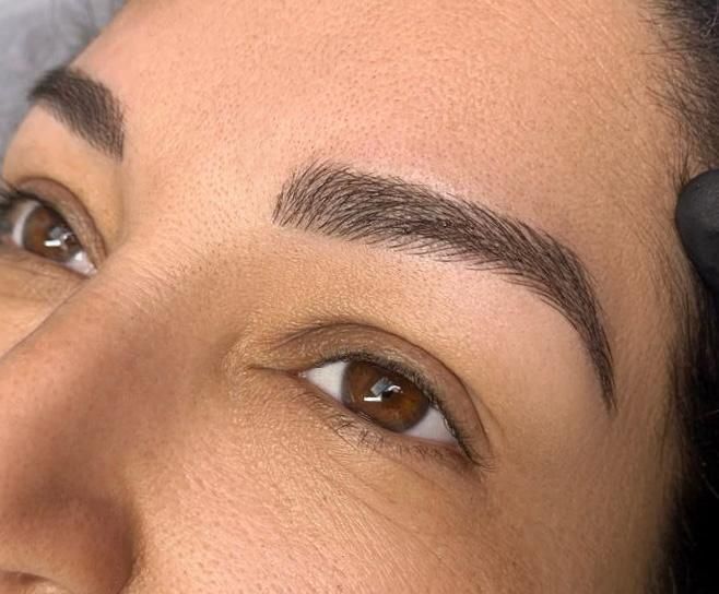 Close-up of woman's face. Perfectly shaped, dark brown eyebrows frame her brown eyes.