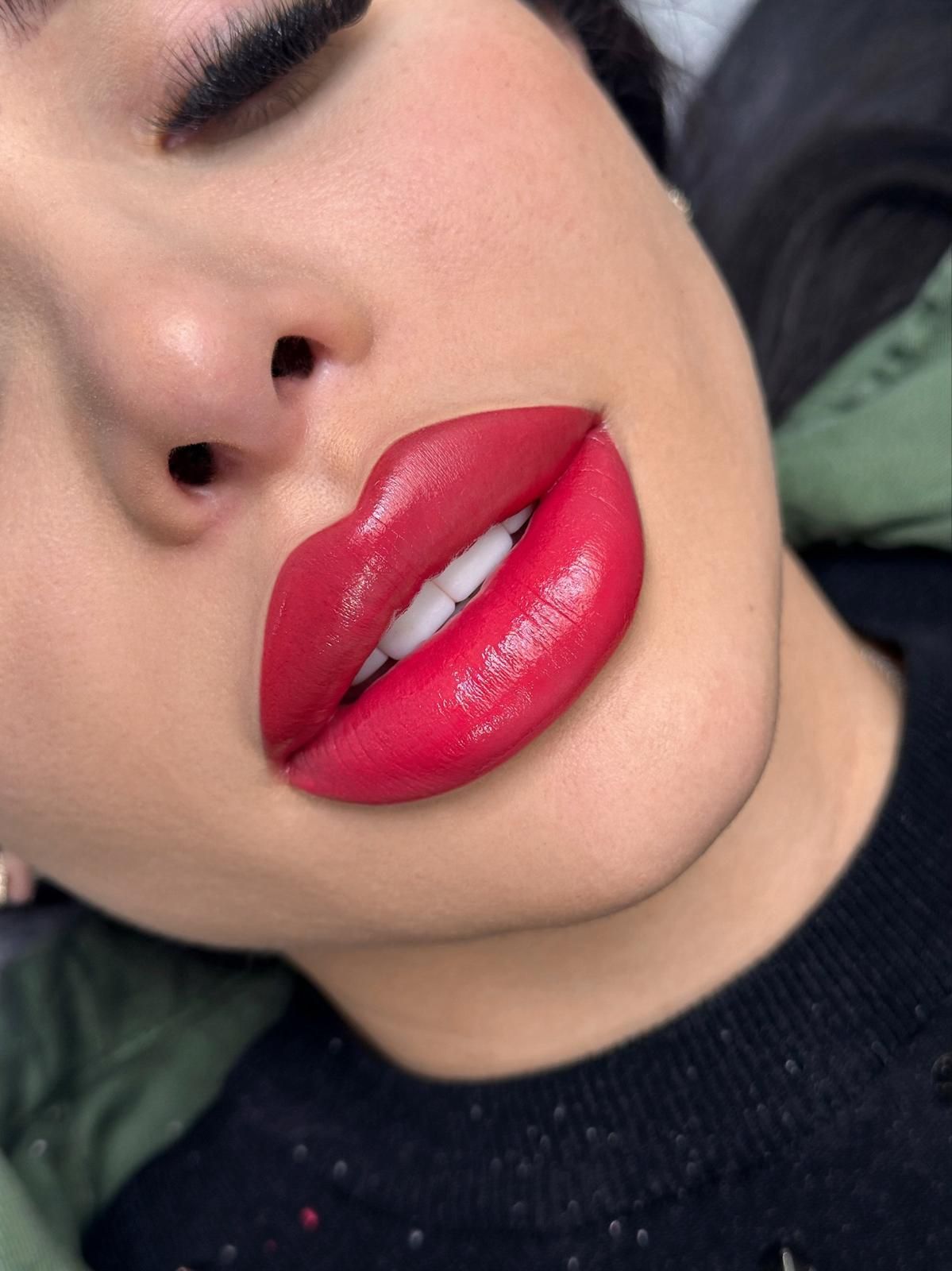 Close-up of a person with full, red lips. The lips are glossy and well-defined, with a slightly darker outer edge.
