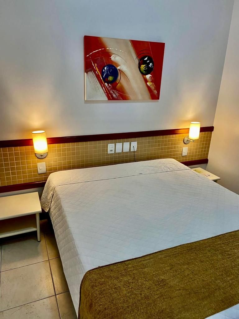 Um quarto de hotel com uma cama grande e uma pintura na parede acima da cama.
