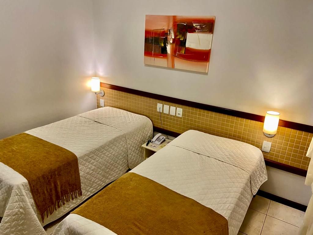 Um quarto de hotel com duas camas e um quadro na parede.