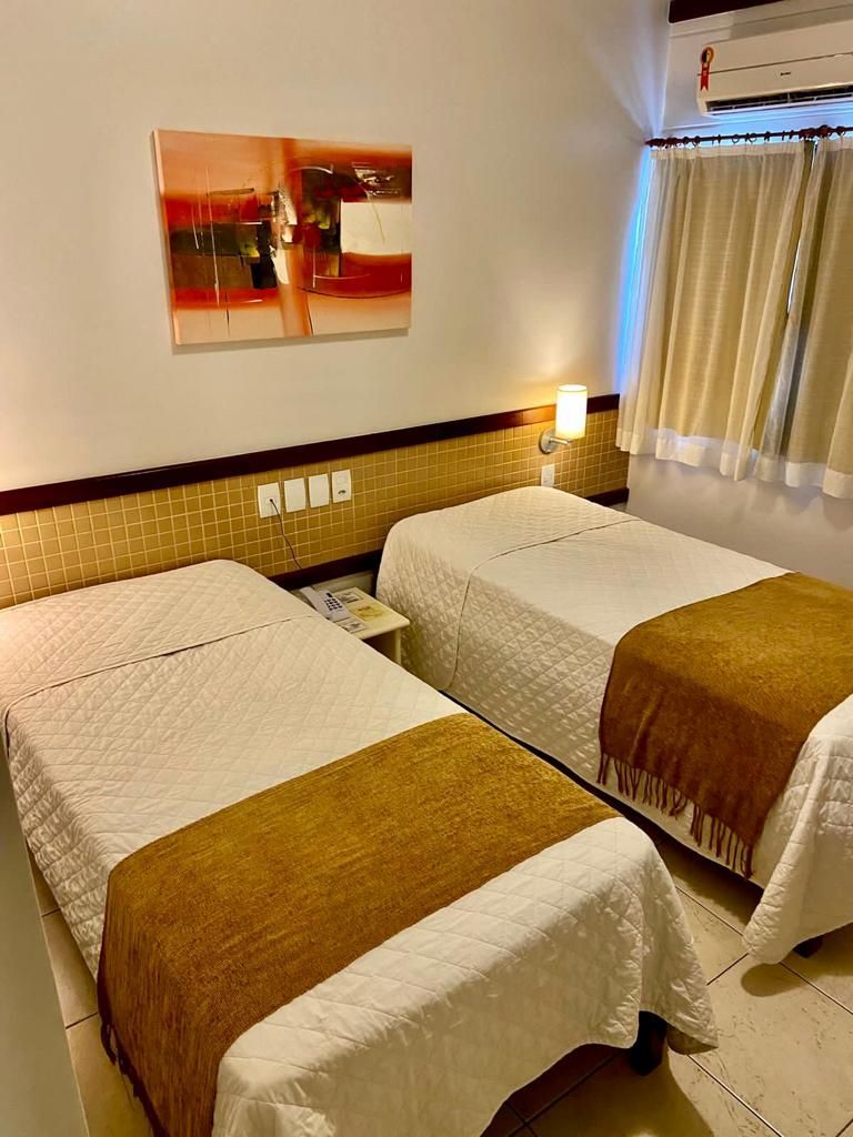 Um quarto de hotel com duas camas e um quadro na parede.