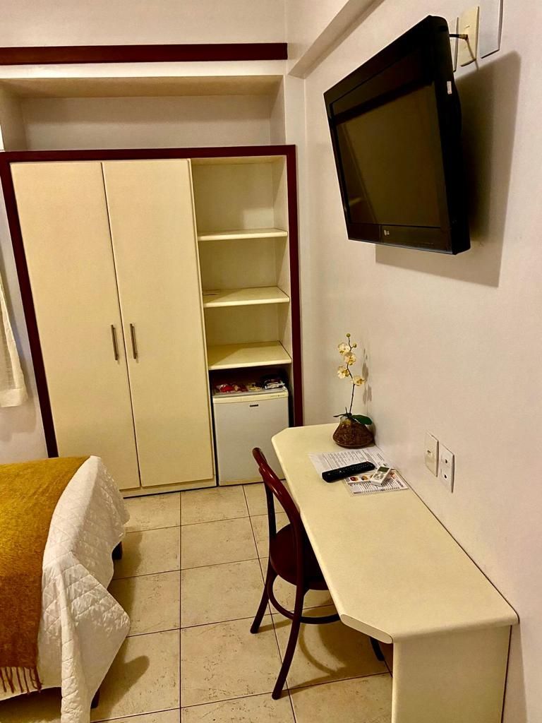 Um quarto de hotel com cama, mesa, cadeira e televisão.