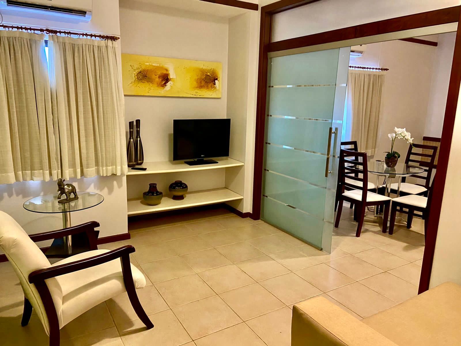 Uma sala de estar com porta de vidro deslizante que dá acesso a uma sala de jantar.