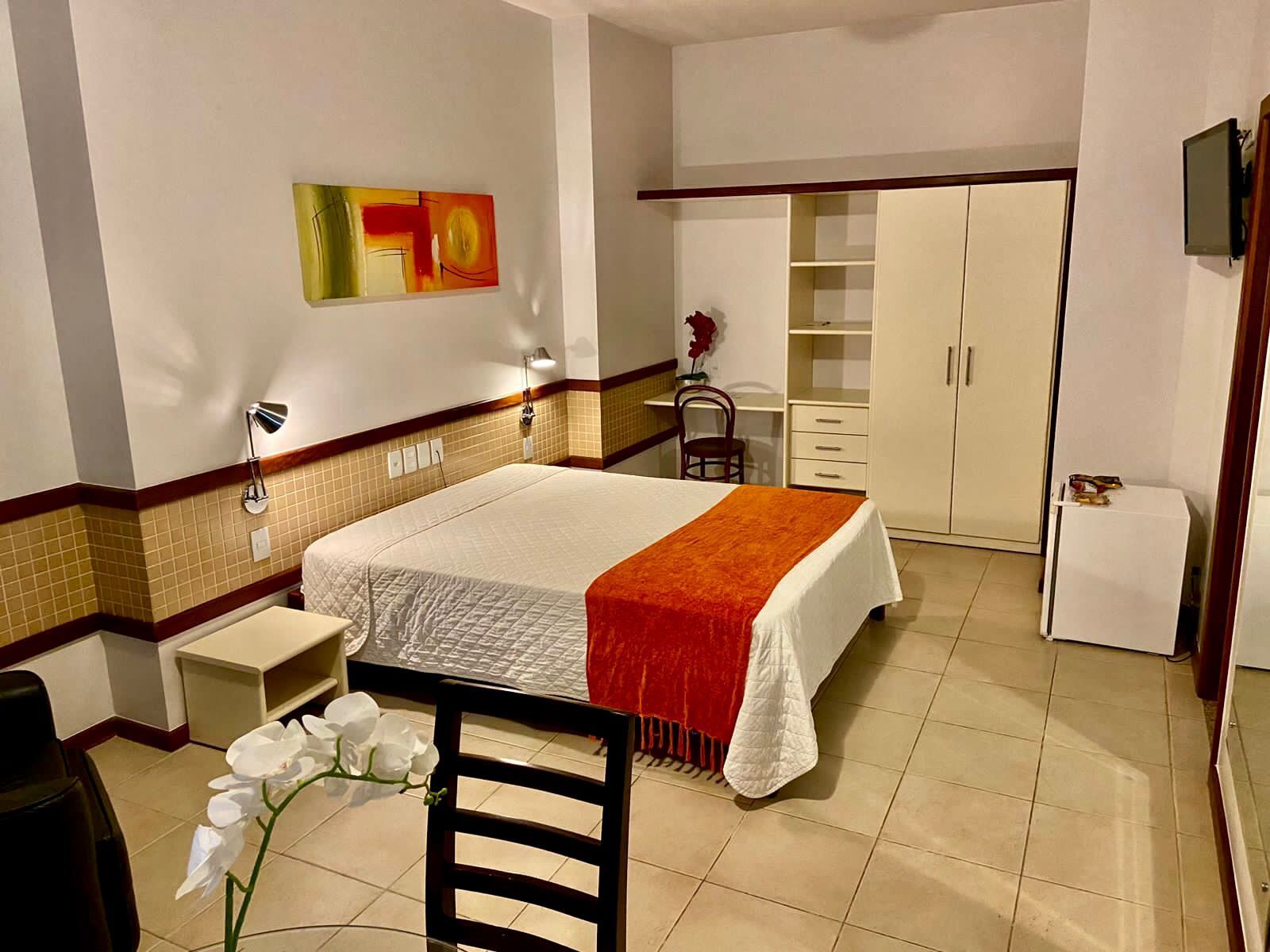 Um quarto do hotel Portal da Princesa com cama king size e uma cadeira.