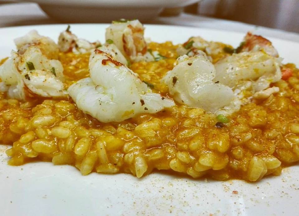 Un piatto bianco con sopra riso e gamberi su un tavolo.