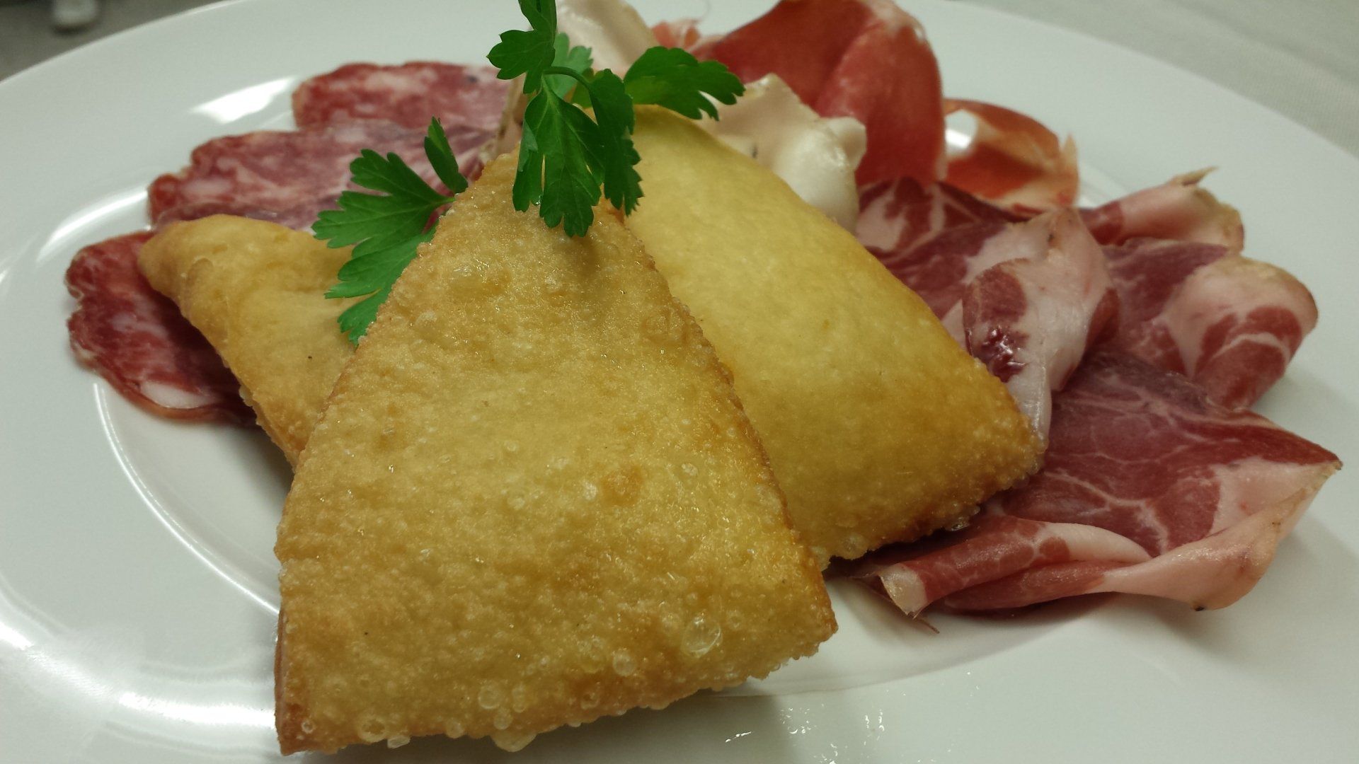 Un piatto bianco con sopra cibo fritto e carne.