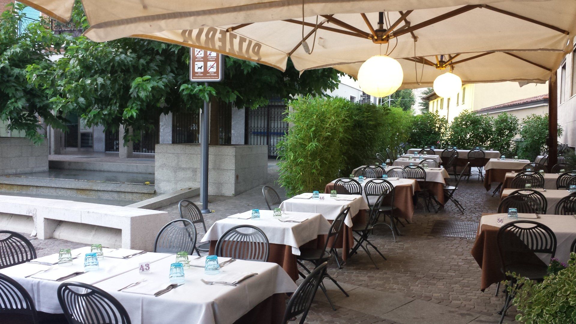 Un ristorante con tavoli e sedie sotto gli ombrelloni e un cartello che dice