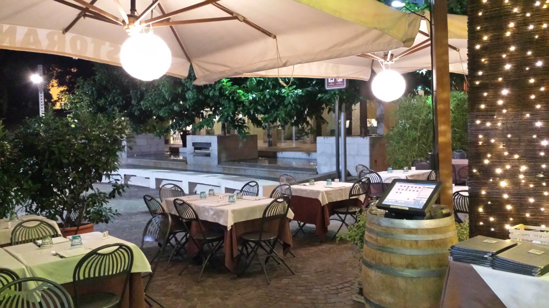 Un ristorante con tavoli e sedie sotto gli ombrelloni di notte