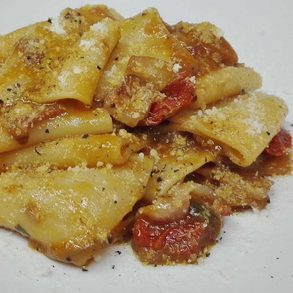Un primo piano di un piatto di pasta con pomodori e formaggio