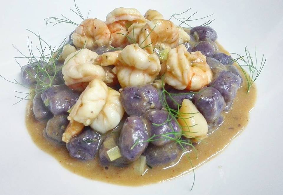 Un primo piano di un piatto di cibo con gamberi e patate