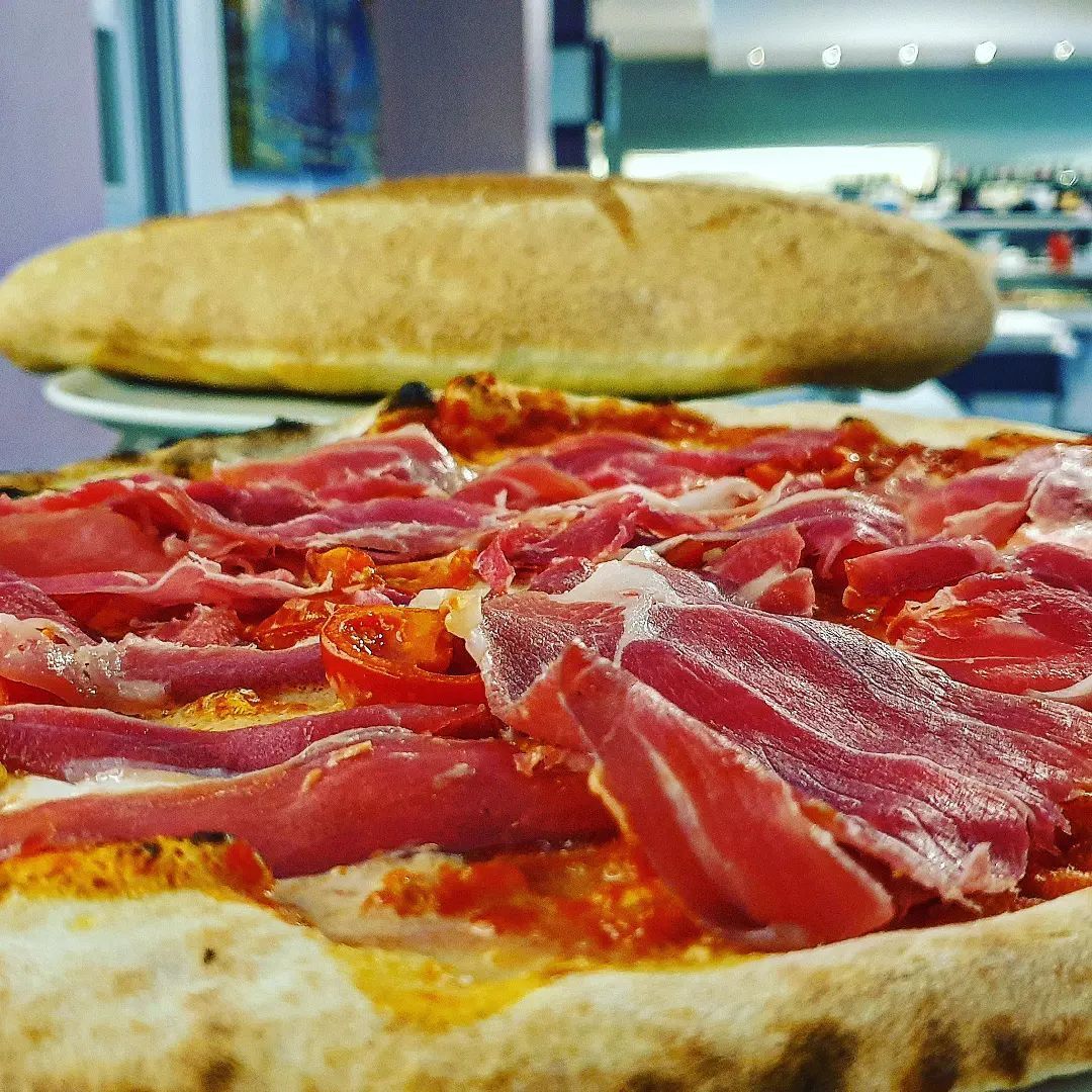 Un primo piano di una pizza con pancetta e pomodori