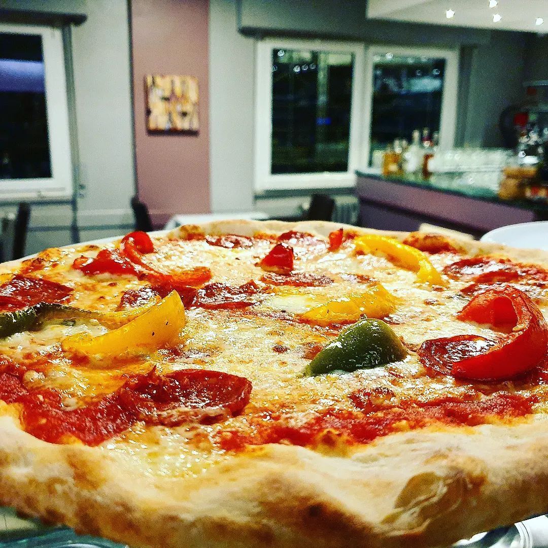 Una pizza viene cotta in un forno a legna.