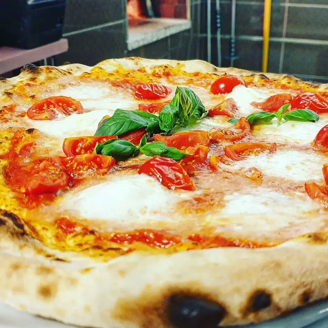 Una pizza con pomodori e basilico è su un piatto.