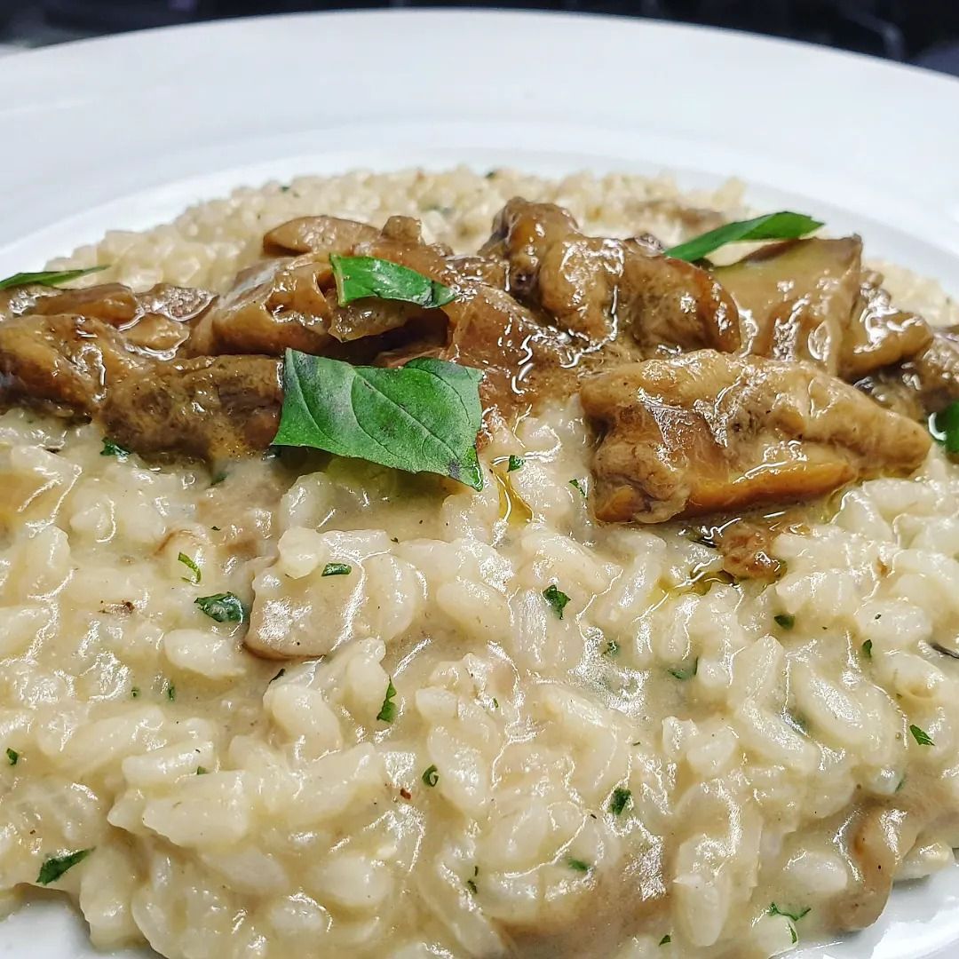 Un piatto bianco con riso e funghi su un tavolo.