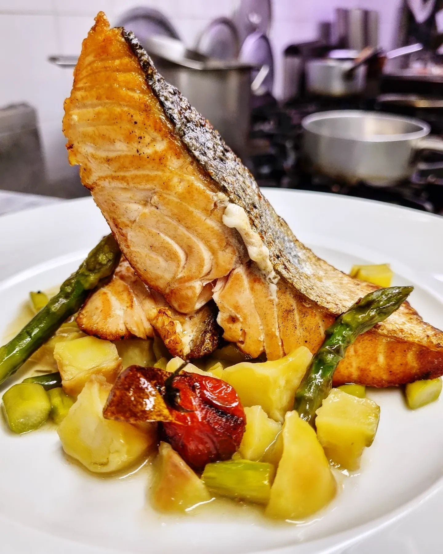Un piatto bianco condito con salmone, asparagi e patate