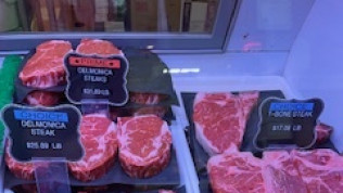 A variety of steaks are displayed in a butcher shop.