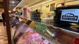 A meat display case in a butcher shop with a sign that says aaron 's fresh meats.