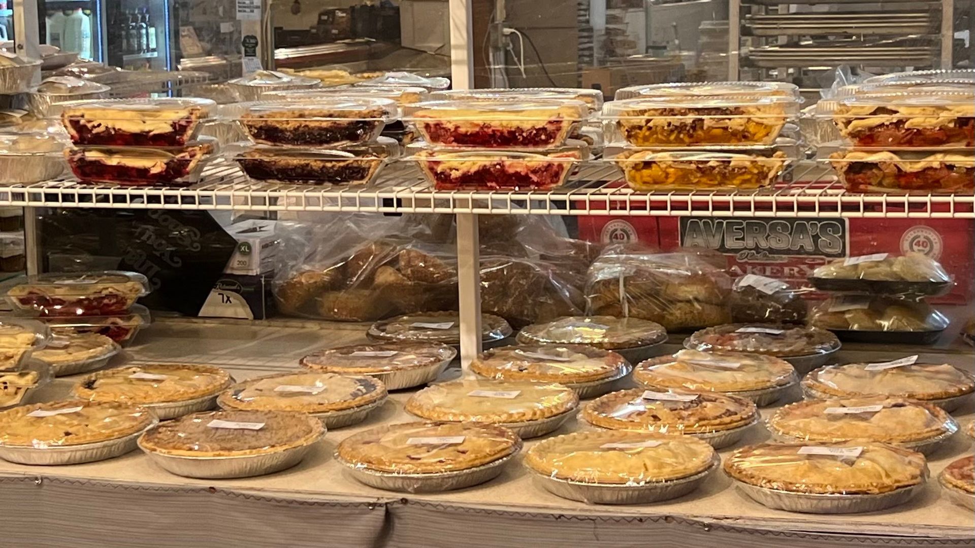 A display case filled with lots of pies in plastic containers.