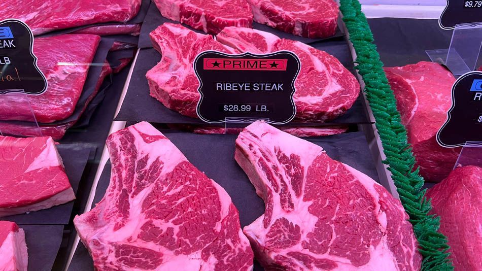 A variety of steaks are displayed in a butcher shop.