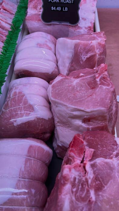A variety of pork cuts are displayed in a butcher shop.