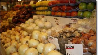 A display of fruits and vegetables including onions and apples