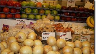 A display of fruits and vegetables including onions and apples