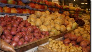 A display of potatoes and apples in a grocery store