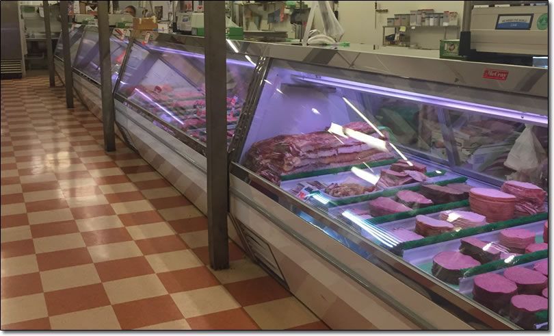 A butcher shop with a checkered floor and display cases filled with meat.