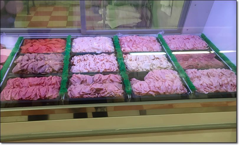 A variety of meats are displayed in a butcher shop.