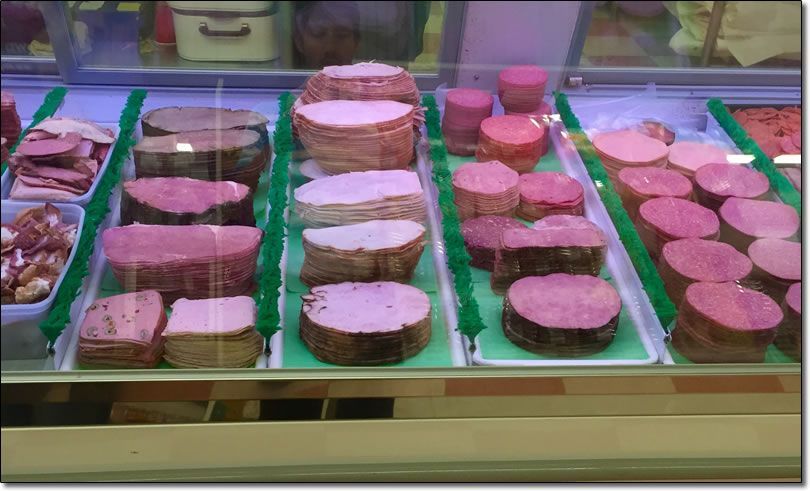 A variety of meats are displayed in a glass case