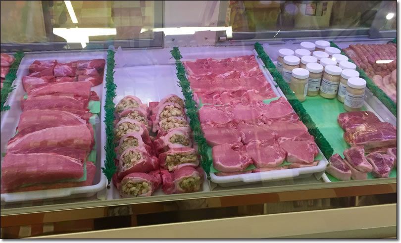 A variety of meats are displayed in a butcher shop.