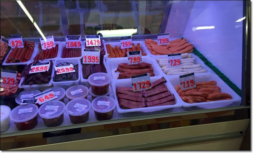 A display case filled with a variety of meats and sauces